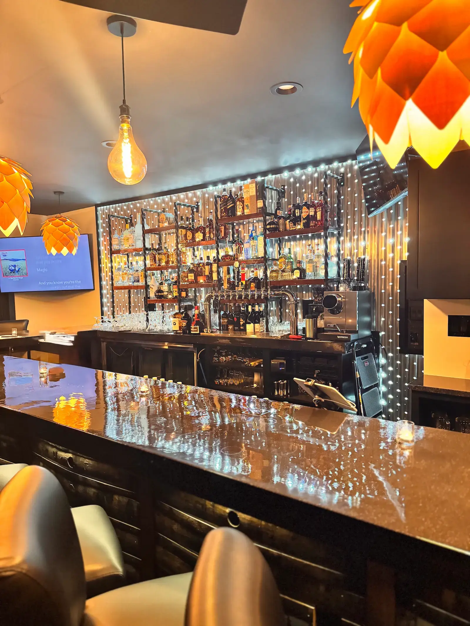 View of the bar with string lights and artichoke pendant lamps