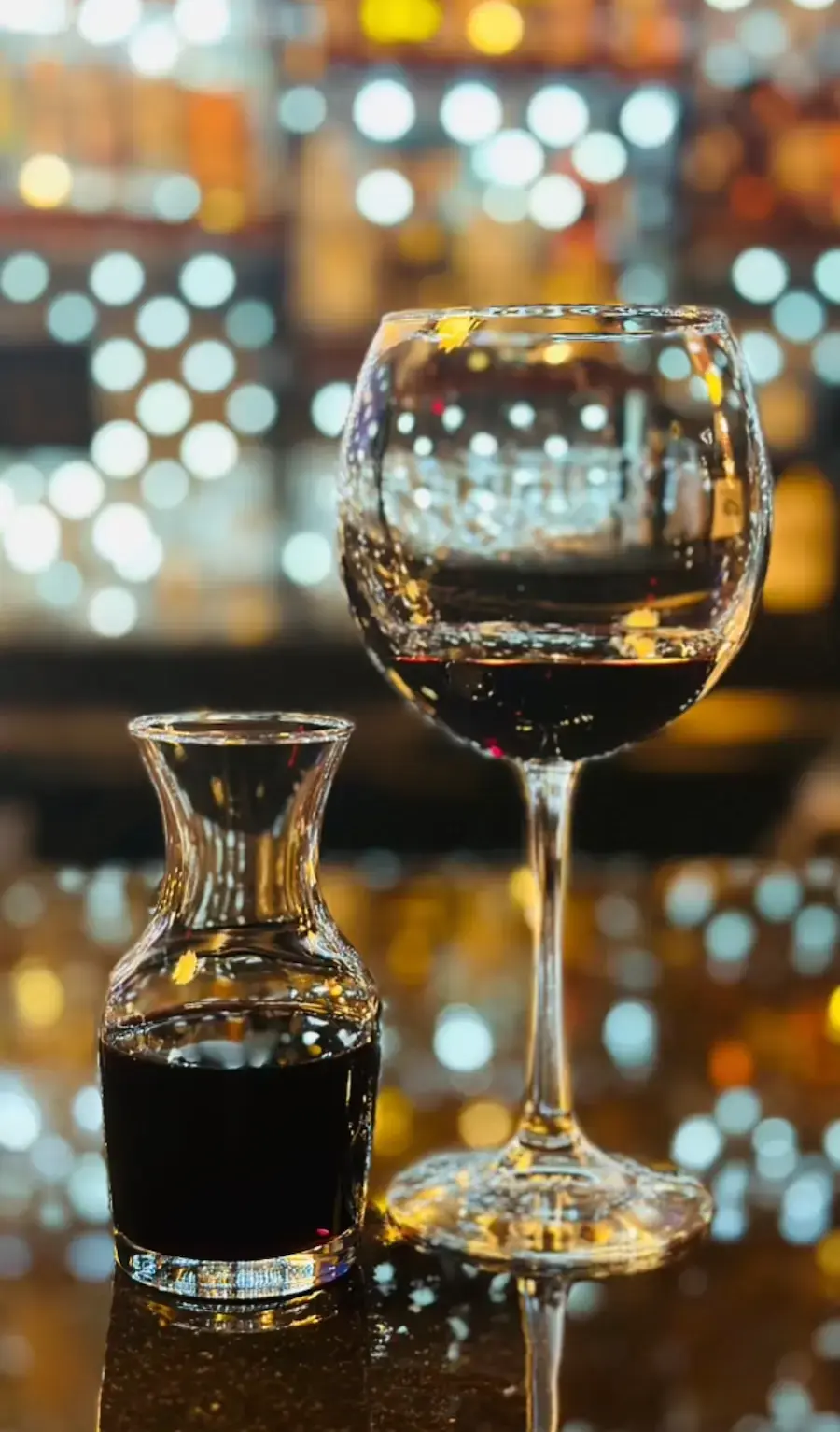 Red wine glass and decanter with bokeh bar lights